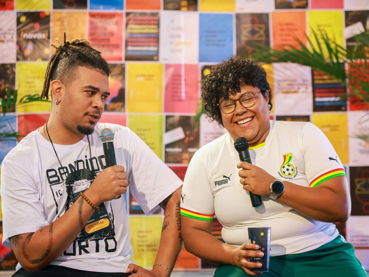 Duas pessoas rindo enquanto conduzem uma conversa ao microfone